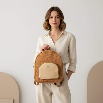 Woman holding a brown backpack against a plain background