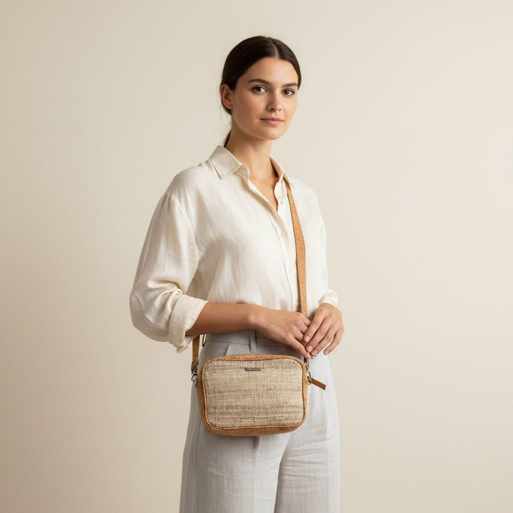 Woman holding a woven crossbody bag against a plain background